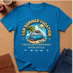A bright blue graphic t-shirt laid flat on a cork background, featuring a retro-style summer vacation design with a blue van, palm tree, beach, and the text 'VAN SUMMER VACATION' and 'DRIVE INTO SUMMER WITH STYLE.' Styled flat-lay props include an apple, coffee cup, notebook, and jeans.