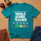 Teal t-shirt with 'Battery Life of a Middle School Teacher' graphic on a cork background with accessories.