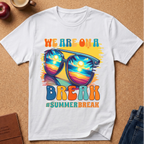 White T-Shirt says "We are on a break #SUMMERBREAK" with a graphic image of Sunglasses reflecting a beach sunset.